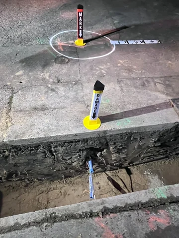 Marker posts identifying a damaged utility at an open excavation