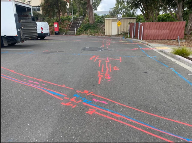 Parking area marked with red and blue utility runs traced across the asphalt