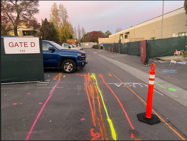 Site access road marked with red, orange, yellow, green and pink locate paint denoting different underground utilities